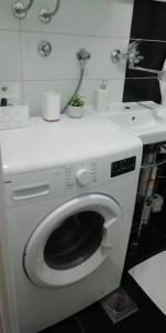 a white washing machine in a bathroom with a sink at Apartment M&A in Osijek