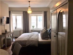 a bedroom with a bed and two windows at Pension Chapeau in Landsberg am Lech