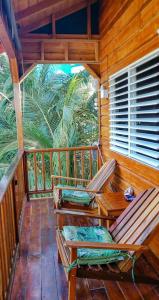 a porch of a cabin with two chairs and a table at The Tranquila Caye- Gold Standard Certified in Caye Caulker