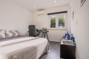 a bedroom with a bed and a desk and a window at Casa Papagaios in Zambujal de Cima