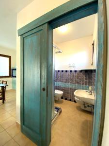 baño con puerta azul y lavamanos en Artemisia Sardegna en Tergu