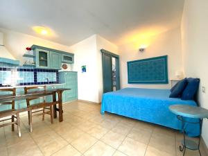 a bedroom with a blue bed and a kitchen at Artemisia Sardegna in Tergu