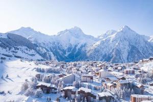 a town covered in snow with mountains in the background at 2 Alpes-locations Studio 4 personnes in Les Deux Alpes
