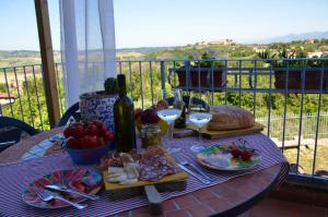 einen Tisch mit Speisen und Wein auf dem Balkon in der Unterkunft Casa Vacanze Magnolia in Terricciola