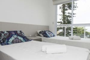 a white bedroom with two beds and a window at Luxo Vista Mar a 50 m da Praia nos Ingleses ING9302 in Florianópolis