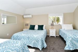 a bedroom with two beds and two windows at Moa Place - Christchurch Holiday Homes in Christchurch