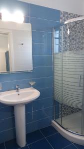 a bathroom with a shower, sink, and mirror at Filoxenia Apartments & Studios in Theologos