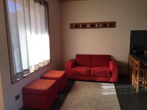 sala de estar con sofá rojo y taburete en Loft Pucon, en Pucón