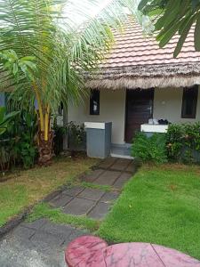 una casa con una palmera delante de ella en BB Homestay Two, en Uluwatu