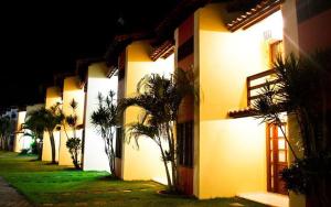 a lit up building with palm trees in front of it at Meu Porto Seguro - Taperapuã in Porto Seguro