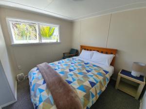 a bedroom with a bed and two windows at Punakaiki Beach Camp in Punakaiki