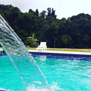 uma fonte em frente a uma piscina com um banco em Recanto Das Borboletas em São Roque