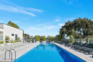 a swimming pool with chaise lounge chairs next to a building at Luxury 2 bdrm in Watson at Walkerville with Balcony, FREE carpark, near Adelaide CBD in Broadview