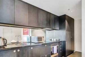 a kitchen with brown cabinets and a microwave at Luxury 2 bdrm in Watson at Walkerville with Balcony, FREE carpark, near Adelaide CBD in Broadview