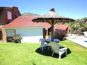 a table and two chairs under a umbrella in a yard at Chalets Los Abedules in Villa General Belgrano