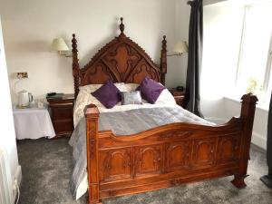 Un dormitorio con una gran cama de madera con almohadas moradas en The North Cliff Hotel en Lynton