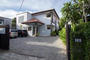 una casa blanca con un estacionamiento delante de ella en Bali Paradise Apartments, en Sanur
