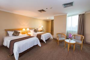 Cette chambre d'hôtel comprend deux lits, une table et des chaises. dans l'établissement Guangzhou New Century Hotel, à Huadu