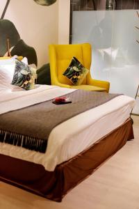 a bedroom with a bed with a yellow chair at Sojourn Spa Hotel Ipoh in Ipoh