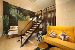 a living room with a staircase and a yellow couch at Sojourn Spa Hotel Ipoh in Ipoh