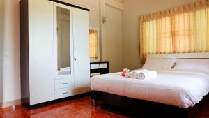 een slaapkamer met een groot wit bed en een spiegel bij Narakorn House in Buriram +5 foto's