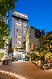 Un grand bâtiment avec des motos garées devant lui dans l'établissement Imperial Hotel & Spa, à Hanoï