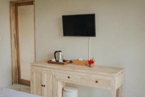 a wooden table with a television on a wall at Auma Villa by Prasi in Ubud