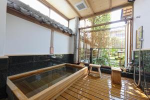a hot tub in a room with large windows at Arashiyama Benkei in Kyoto