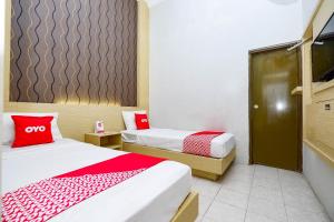 um quarto com 2 camas e almofadas vermelhas em OYO 2436 Hotel Kencana em Tegal