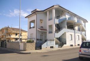 ein weißes Gebäude an der Straßenseite in der Unterkunft Casa Vacanze Nuraghe Talia in Olmedo