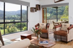 uma sala de estar com cadeiras, uma mesa e janelas em Greenlee Cottages em Canungra