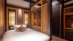 - une chambre avec des murs en bois et un lit avec des draps blancs dans l'établissement Floral Guesthouse Huangshan Shuxiang Gongyuanli, à Tangkou