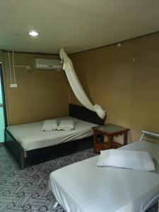 Cette chambre comprend 2 lits et une table. dans l'établissement Puteri Salang Inn, à l'Île Tioman