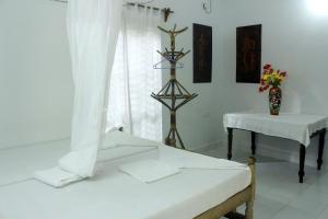 a room with a bed and a table and a window at Jickys Nest in Varkala
