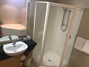 a bathroom with a shower and a sink at Harbour City Motor Inn & Conference in Tauranga
