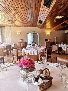 un comedor con mesas y sillas con flores en la mesa en Hotel Vianorte, en Maia