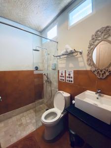 a bathroom with a toilet and a shower and a sink at Jukung Guest House in Sanur