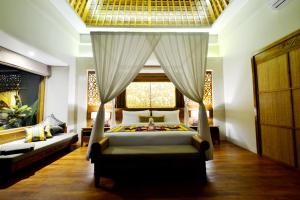 a bedroom with a bed and a window and a couch at Kenran Resort Ubud By Soscomma in Ubud