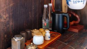 - un plateau avec des tasses et des bouteilles sur une table dans l'établissement Floral Guesthouse Huangshan Shuxiang Gongyuanli, à Tangkou