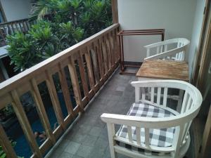 a balcony with two white chairs and a table at Jukung Guest House in Sanur