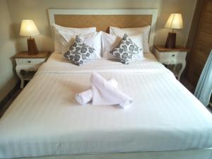 a large white bed with two mitts on it at Jukung Guest House in Sanur