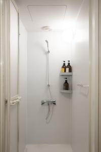 a white bathroom with a shower and a sink at UNPLAN Village Hakuba in Otari