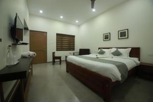 a bedroom with a bed and a desk and a television at GREEN PLANET HOTEL in Mattanūr