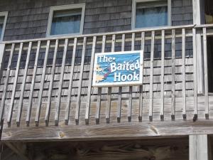 a building with a fence with a sign on it at THE BAITED HOOK cottage in Frisco