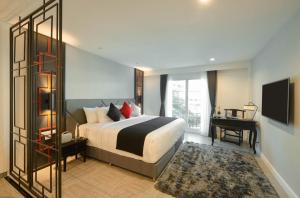 a bedroom with a bed and a desk and a television at Villa De Pranakorn in Bangkok