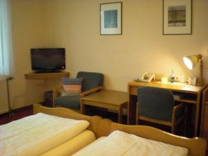 a hotel room with a bed and a desk and a tv at Hotel Garni Stadt Friedberg in Friedberg