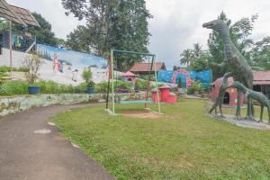 een park met een speeltuin met dinosaurusbeelden in het gras bij RedDoorz Resort Syariah @ Batu Apung Purwakarta in Purwakarta