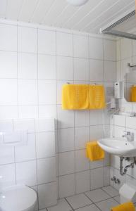 a bathroom with a sink and a toilet and yellow towels at Gästehaus Kleine Kalmit in Landau in der Pfalz