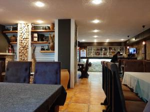 a dining room with tables and chairs and a person in the kitchen at Апартамент КАРЛИН in Pamporovo