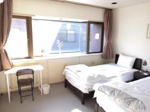 a room with two beds and a window and a chair at Tiny GuestHouse Umekoji 梅小路 in Kyoto